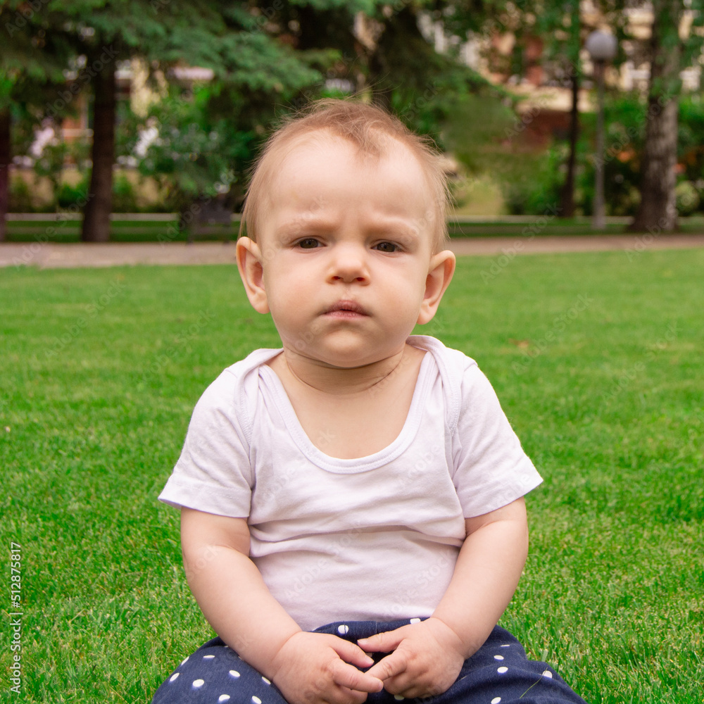 The child sits on the grass alone. Baby is sad and wants to cry The child sits on the grass alone. Baby is sad and wants to cry