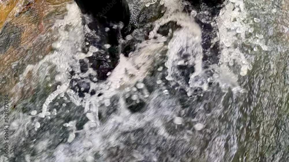 View of water running over boots in a stream, in slow motion View of water running over boots in a stream, in slow motion