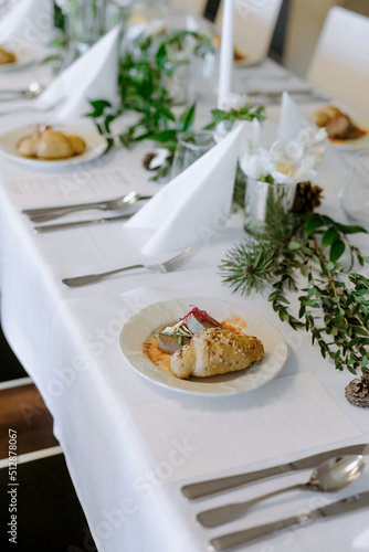 Banquet table with dish.  Dish with croissant and pate.  Decorating the table with flowers and greenery.