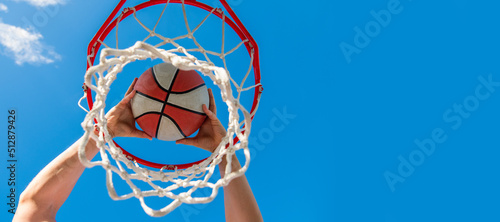 basketball player throws the ball into the hoop on sky background, targeting. Horizontal poster design. Web banner header, copy space.