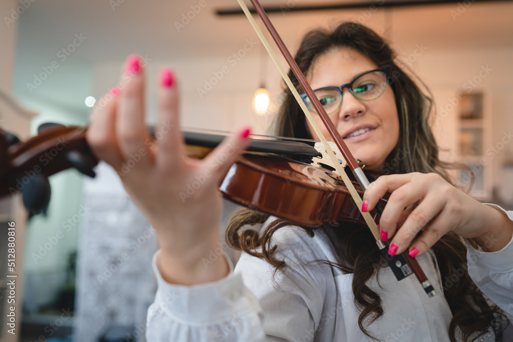 One woman caucasian indoor in her house holding violin and learning to play front view waist up Study from home lifestyle concept One woman caucasian indoor in her house holding violin and learning to play front view waist up Study from home lifestyle concept