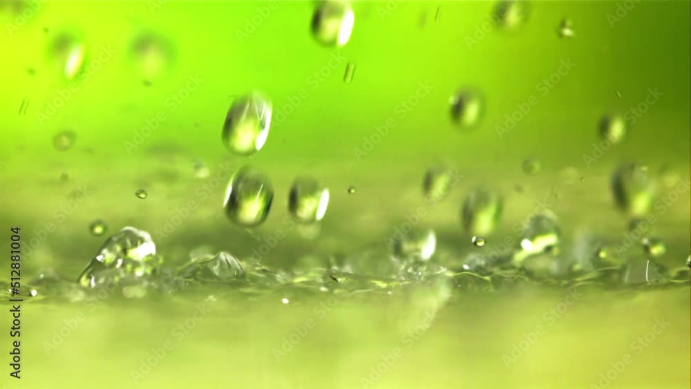 Water droplets fall with splashes. On a green background.Filmed is slow motion 1000 fps. Water droplets fall with splashes. On a green background.Filmed is slow motion 1000 fps.