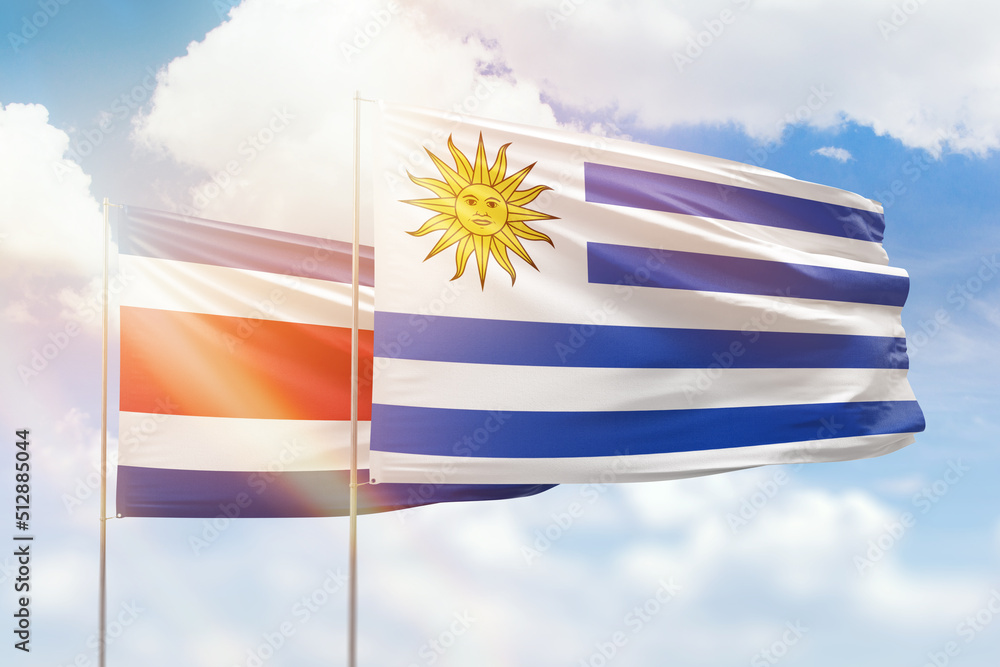 Fototapeta premium Sunny blue sky and flags of uruguay and costa rica