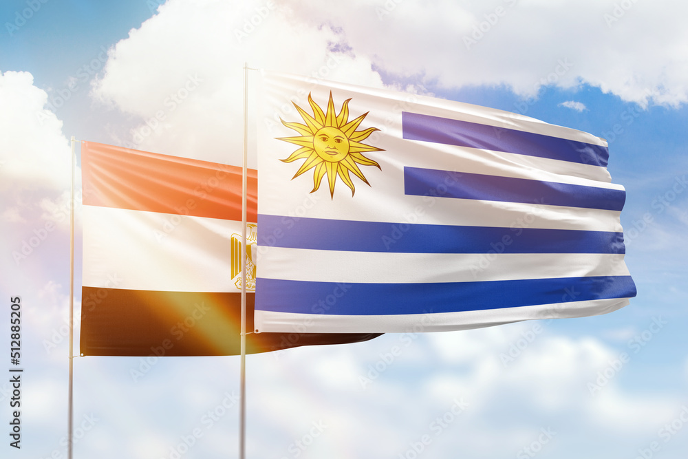 Fototapeta premium Sunny blue sky and flags of uruguay and egypt