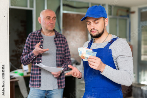 Builder holding cash, disappointed by salary he received from his employer.