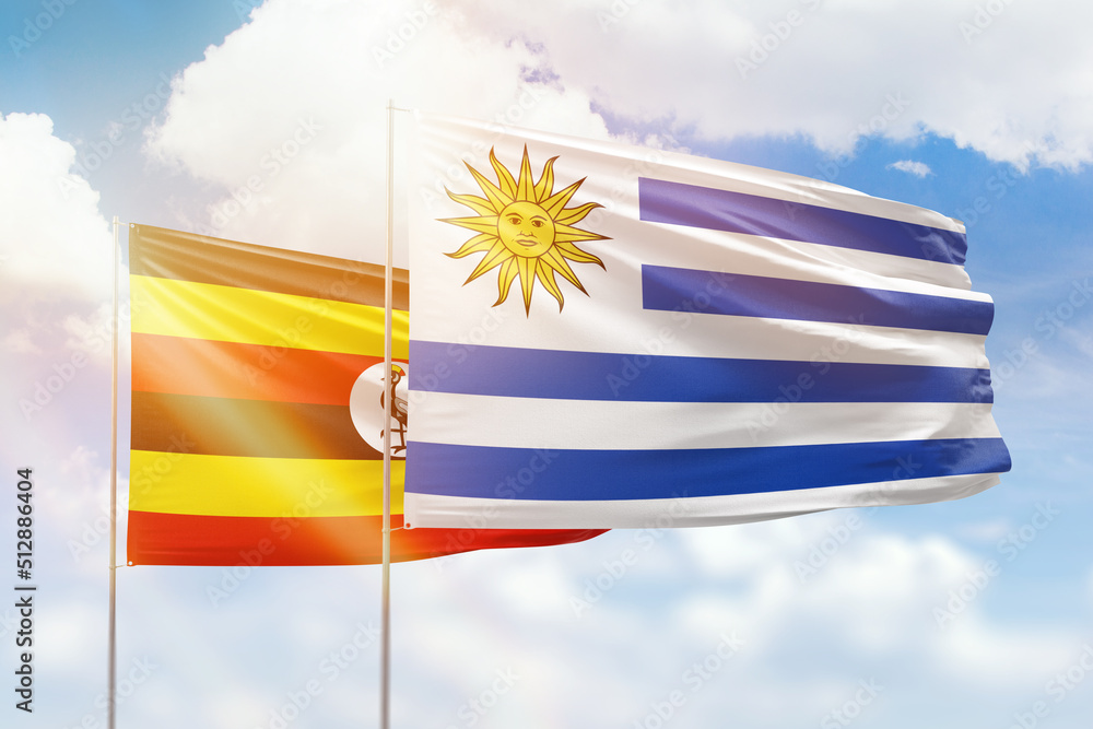 Fototapeta premium Sunny blue sky and flags of uruguay and uganda