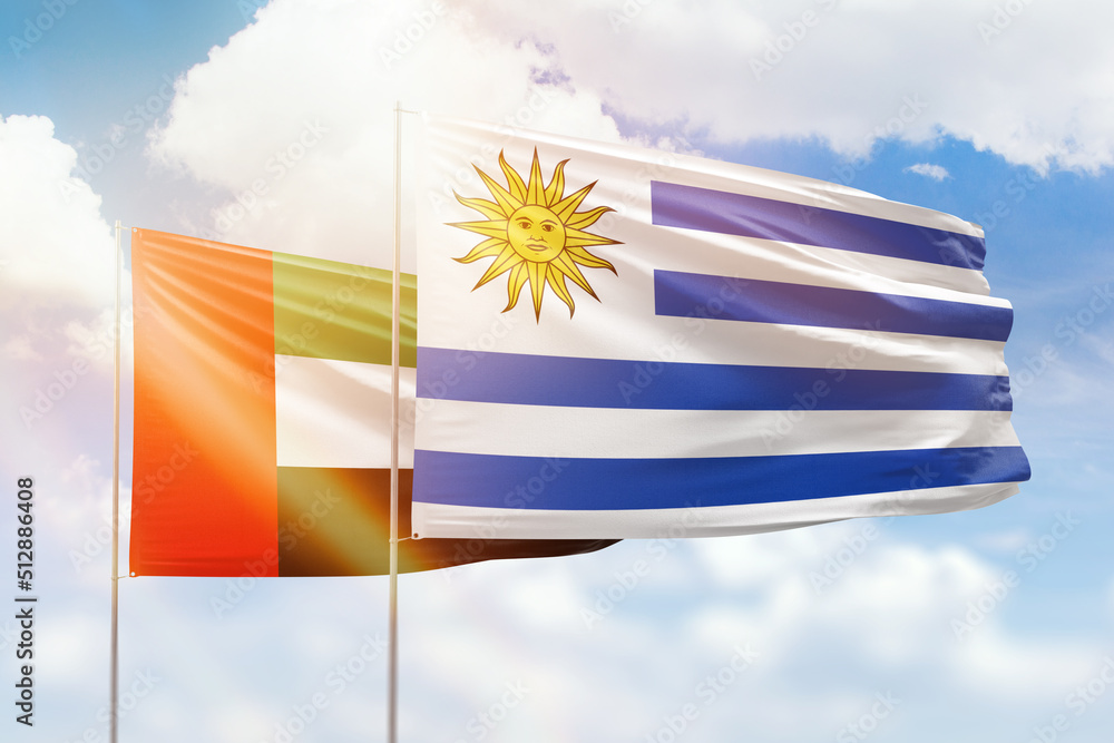 Fototapeta premium Sunny blue sky and flags of uruguay and uae