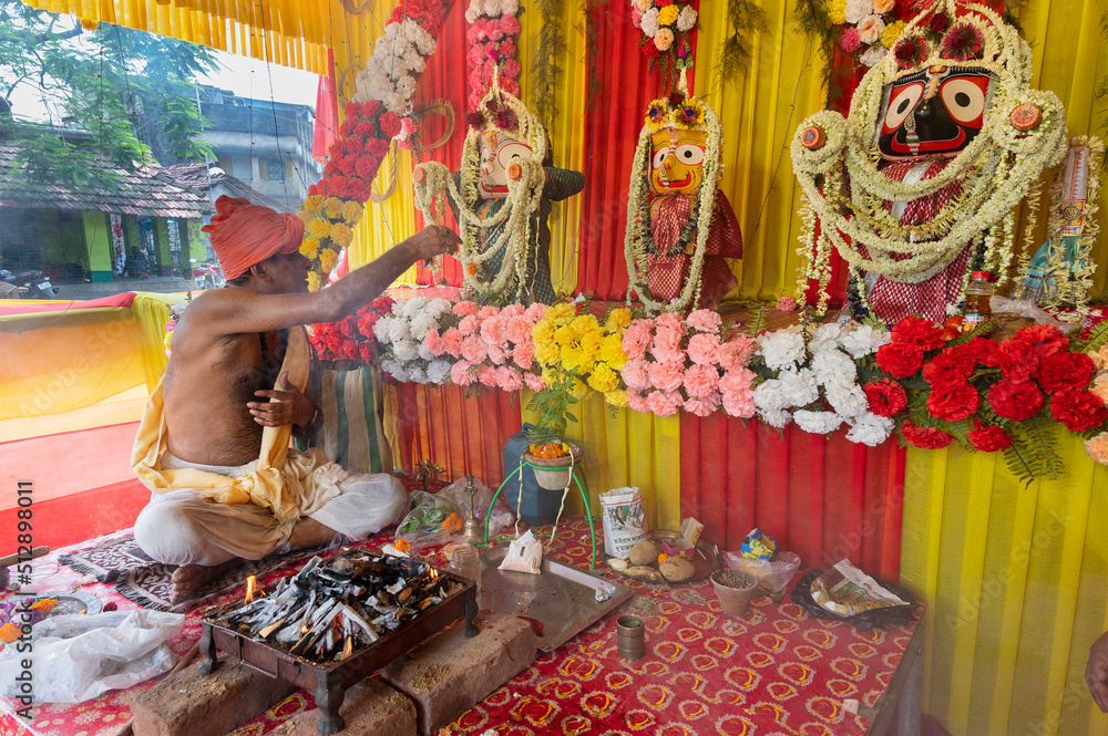 Howrah, West Bengal, India - 29th June 2020 : Hindu priest worshipping idol of God Jagannath, Balaram and Suvodra inside pandal. Ratha jatra festival is famous Hindu festival in India.