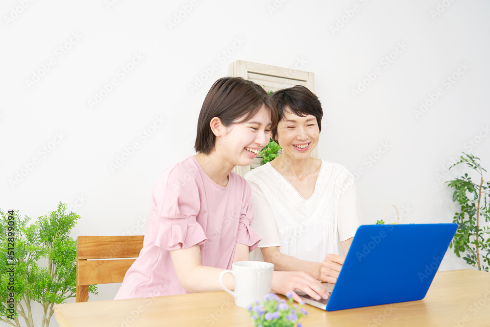 リビングでノートパソコンを見る母親と娘 リビングでノートパソコンを見る母親と娘
