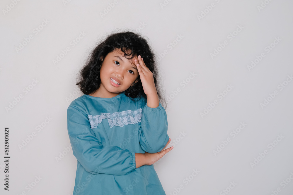 Little Asian girl with curly hair holding her head, isolated over white studio background. Little Asian girl with curly hair holding her head, isolated over white studio background.