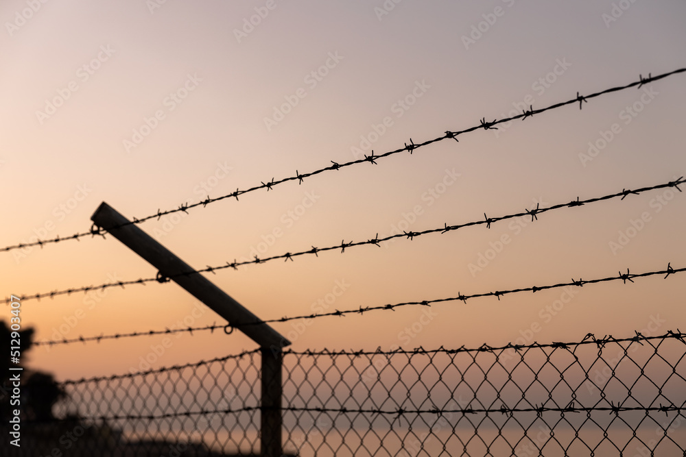 Barbed Wire Fence over Sky and Sea at Sunset Warm Colors Barbed Wire Fence over Sky and Sea at Sunset Warm Colors