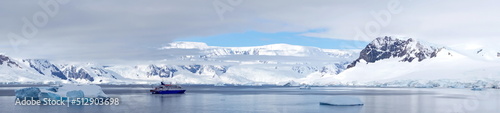 Panorama of an expedition cruise ship in a bay  surrounded by icebergs  at Portal Point  Antarctica