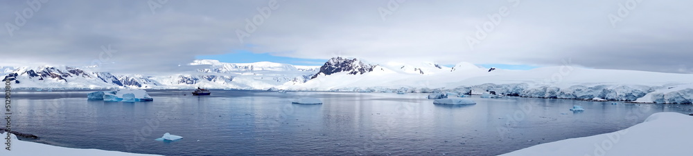 Panorama of icebergs in a bay, surrounded by snow covered mountains, at Portal Point, Antarctica