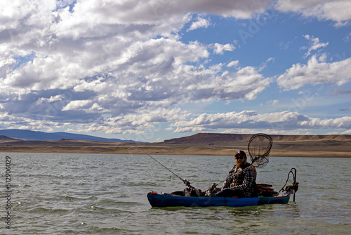 Kayaker Wearing Life Jacket Fishing on Kayak with Trolley Motor and Fishing Poles and Net in Lake Hattie near Laramie Wyoming