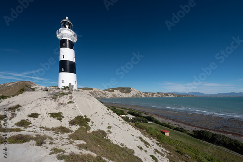 The black and white Cape Campbell Lighthouse with Clifford Bay in the background. Cape Campbell, Marlborough, South Island, New Zealand.
