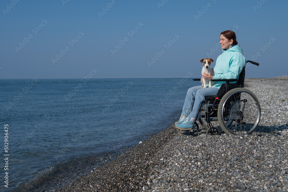 Caucasian woman in a wheelchair with a dog at the sea.