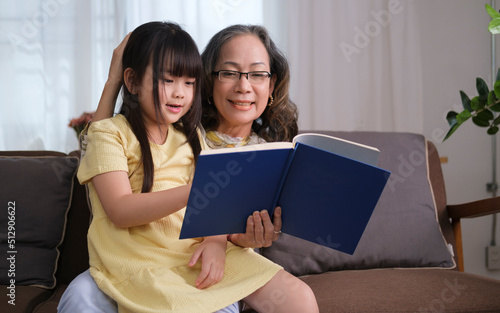 Smiling grandmother telling funny fairy tale story to her little granddaughter.