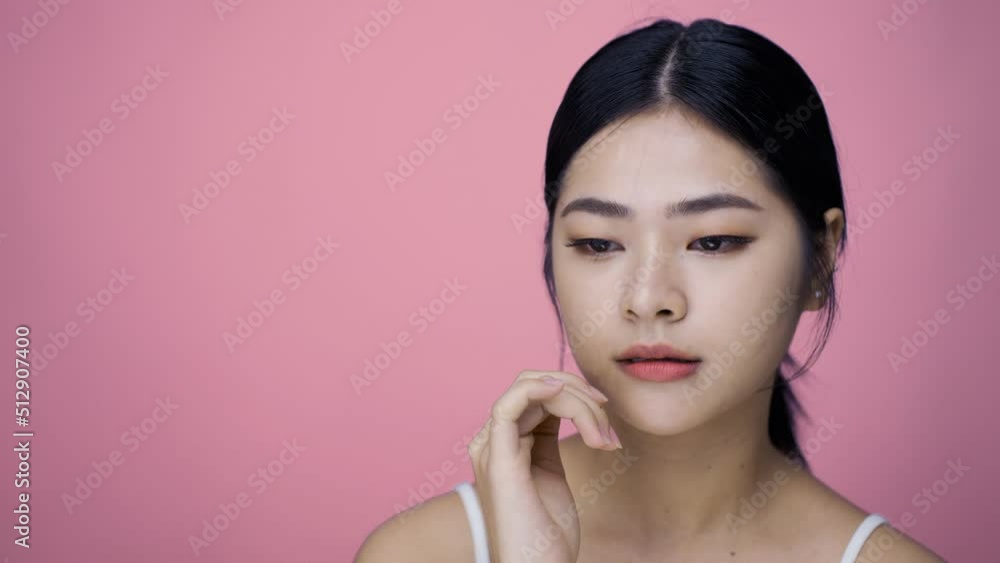 Close up Beauty shot of Beautiful Asian girl looking at camera isolated on pink background Close up Beauty shot of Beautiful Asian girl looking at camera isolated on pink background