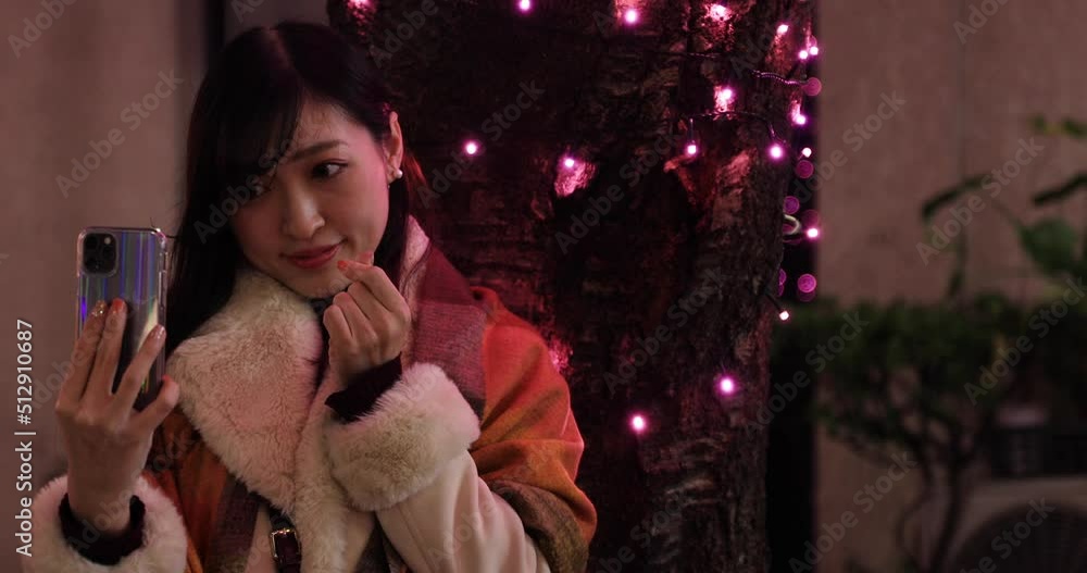 A Japanese girl shooting selfie at night illuminated street in Shibuya close shot A Japanese girl shooting selfie at night illuminated street in Shibuya close shot