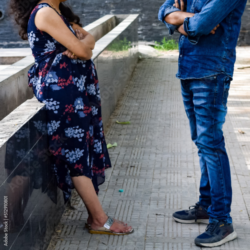 Indian couple posing for maternity baby shoot. The couple is posing in a lawn with green grass and the woman is falunting her baby bump in Lodhi Garden in New Delhi, India