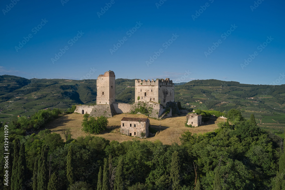 An ancient castle in Italy surrounded by vineyards is a point of interest. Scaliger Castle of d'Illasi in the province of Verona, built in the 10th century. Medieval castle on a hill aerial view.