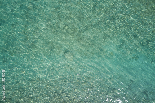 clear water top. Turquoise blurred water top view. Stones at the bottom of the water aerial view.