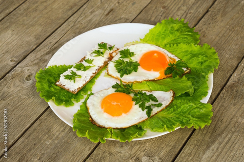 Healthy breakfast - fried eggs, bread with cheese and fresh parsley on a white plate