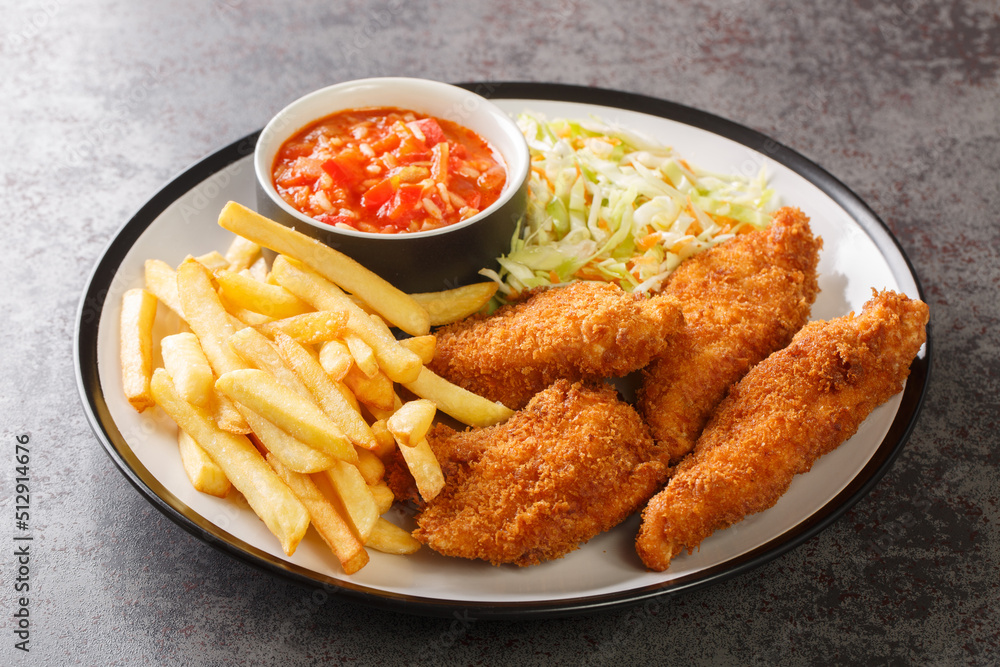 Tasty Breaded chicken with French fries, cabbage salad and spicy sauce close up in the plate on the table. Horizontal Tasty Breaded chicken with French fries, cabbage salad and spicy sauce close up in the plate on the table. Horizontal