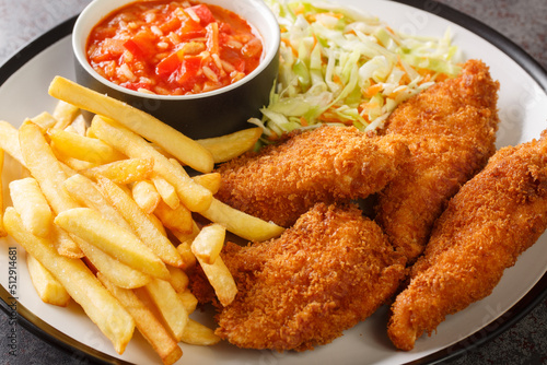 Tableau sur toile Serbian fried chicken with French fries, cabbage salad and hot sauce close up in the plate on the table