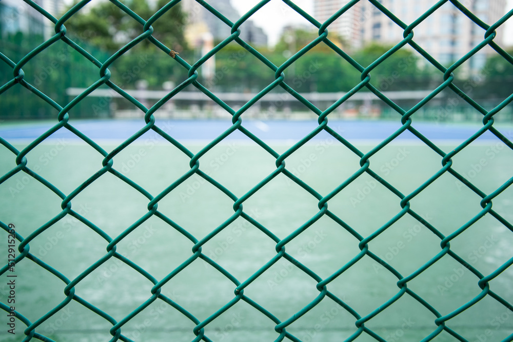 A green steel net that snags the fence of the tennis court. A green steel net that snags the fence of the tennis court.