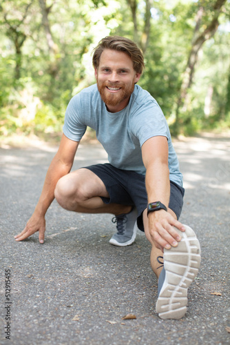 handsome man in sports uniform is stretching outdoors