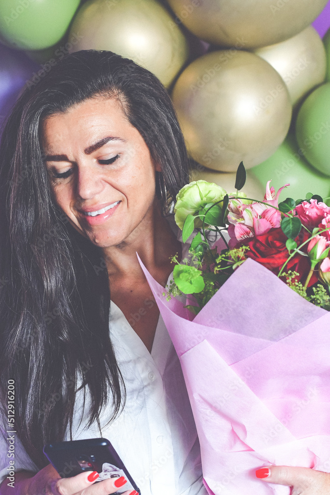Beautiful Smiling Grateful Woman holding a big bouquet of Roses stands with closed eyes near a baloon wall Romantic portrait. Celebrating concept Beautiful Smiling Grateful Woman holding a big bouquet of Roses stands with closed eyes near a baloon wall Romantic portrait. Celebrating concept