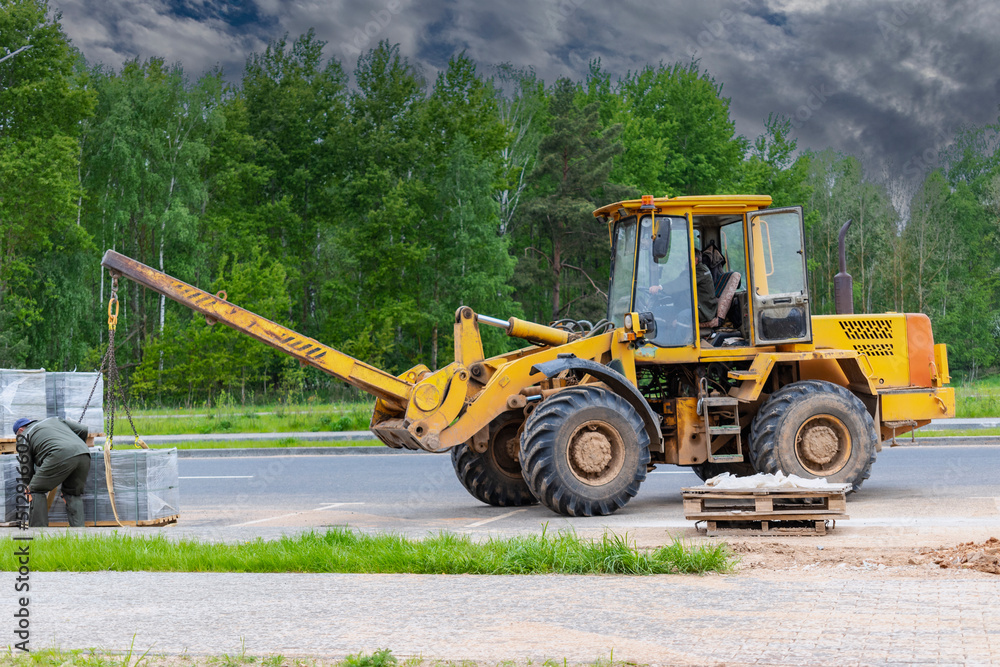Powerful wheel loader for transporting bulky goods at the construction site of a modern residential area. Construction equipment for lifting and moving loads. Powerful wheel loader for transporting bulky goods at the construction site of a modern residential area. Construction equipment for lifting and moving loads.