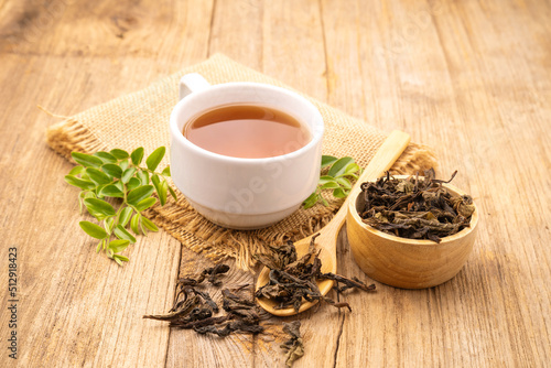 White cup of hot tea and dry tea leaf on wooden table