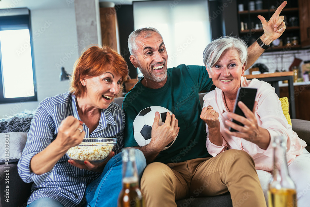 Group of senior friends support favorite sports team together use smartphone app to online bet