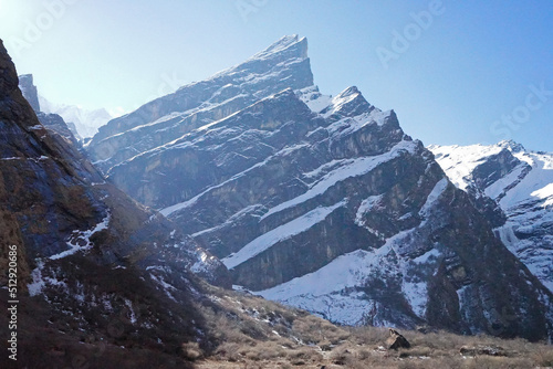 Local Nepali village among natural landscape view of snowcapped mountain cliff and cloudy blue sky- Nepal