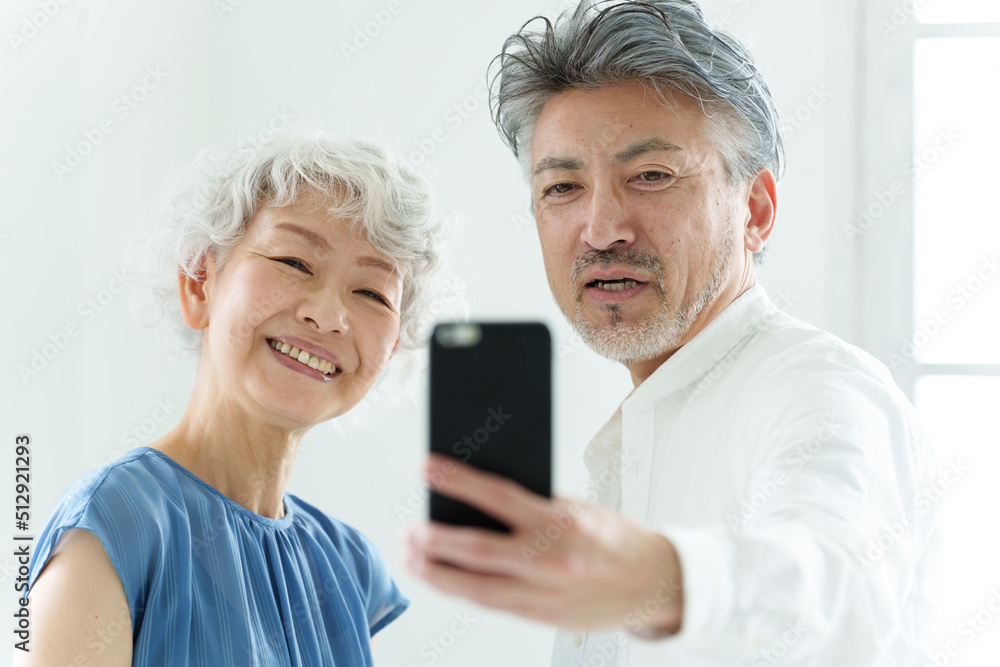 スマートフォンで自撮りをするミドル夫婦 スマートフォンで自撮りをするミドル夫婦