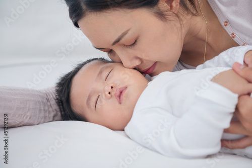 Loving mom carying of her newborn baby at home. Bright portrait of happy mum holding sleeping infant child on hands. Mother hugging her little 6 months old son. Family in the house. Lifestyle.