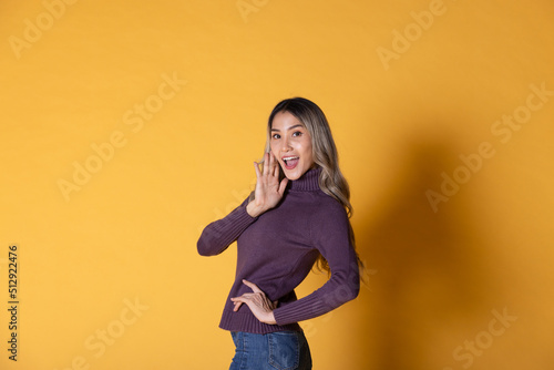 portrait of a beautiful young woman in a purple sweater on a yellow background