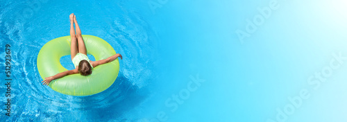 Girl swim in pool with big green rubber ring. Extra wide banner. Copy space for text. Summer leisure activity. Vacation concept.