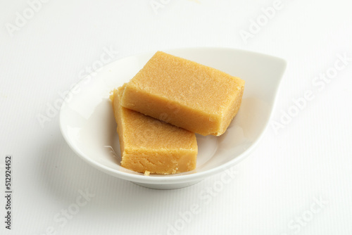 An Indian sweet originated from Mysore made from Ghee called  served on a white plate on a white background