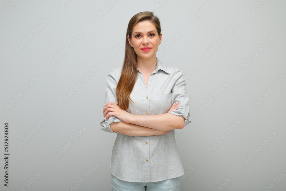 Smiling woman standing with arms crossed, isolated female studio portrait, young lady dressed pants and gray shirt Smiling woman standing with arms crossed, isolated female studio portrait, young lady dressed pants and gray shirt