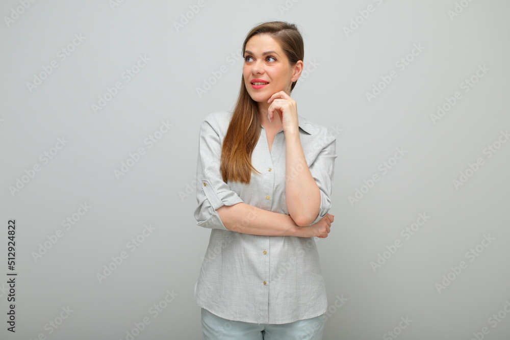 Smiling thinking woman with her chin on hand looking up, isolated female portrait, young lady dressed pants and gray shirt. Smiling thinking woman with her chin on hand looking up, isolated female portrait, young lady dressed pants and gray shirt.