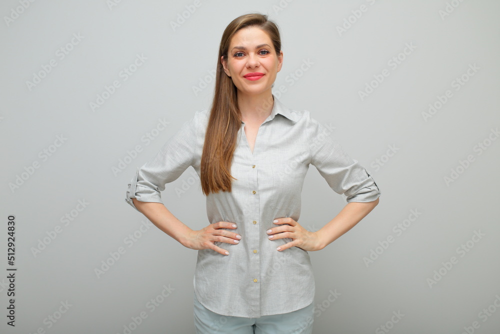 Smiling confident woman standing with hands on hips, isolated female portrait, young lady dressed pants and gray shirt. Smiling confident woman standing with hands on hips, isolated female portrait, young lady dressed pants and gray shirt.