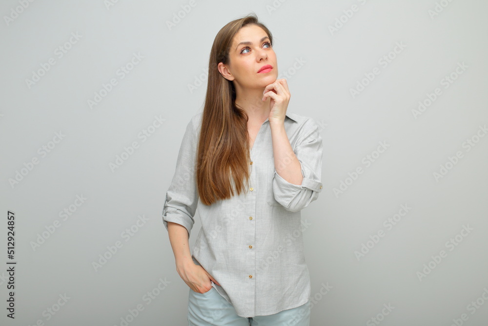 Thinking serious woman touching her face and looking up, isolated female portrait, young lady dressed pants and gray shirt. Thinking serious woman touching her face and looking up, isolated female portrait, young lady dressed pants and gray shirt.