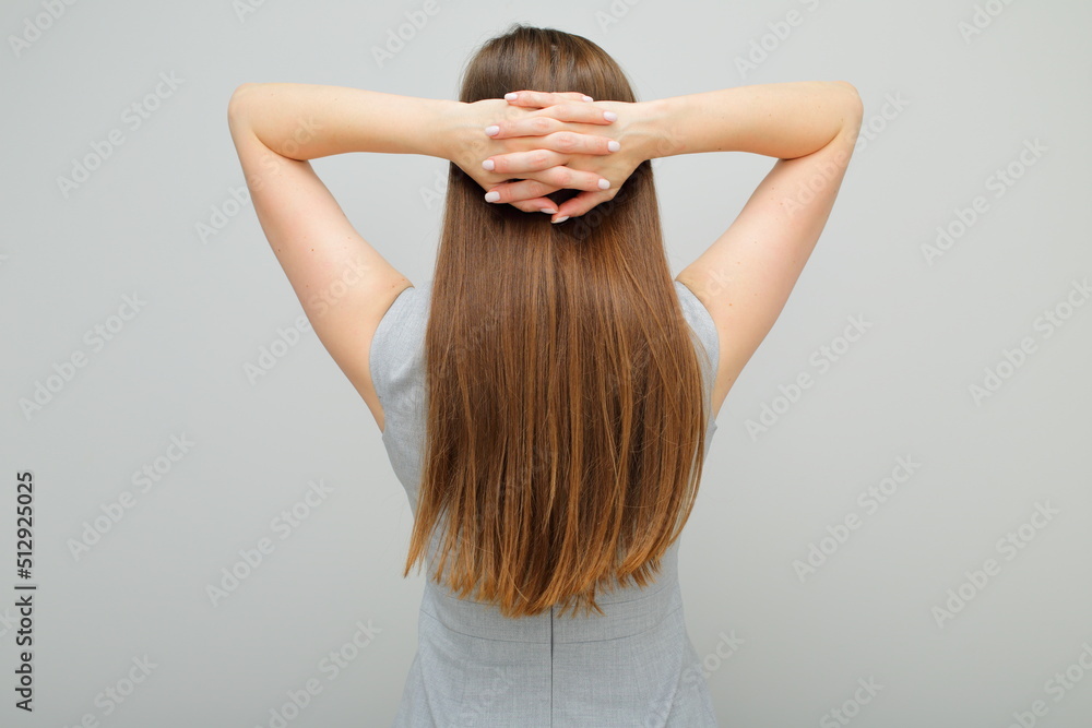 Woman in business dress standing back and holding hands on head, female portrait with long hair. Back view. Rear view. Woman in business dress standing back and holding hands on head, female portrait with long hair. Back view. Rear view.