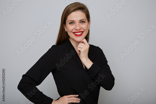 Smiling confident business woman or office worker in black shirt holding hands on hip and touching her chin, isolated female portrait. photo