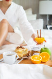 woman having breakfast on white bed