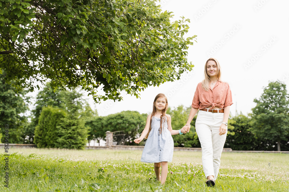Obraz premium Mom and daughter walking and having fun together in the park. Happy family lifestyle. Love in family. Hapiness of mother and her child.