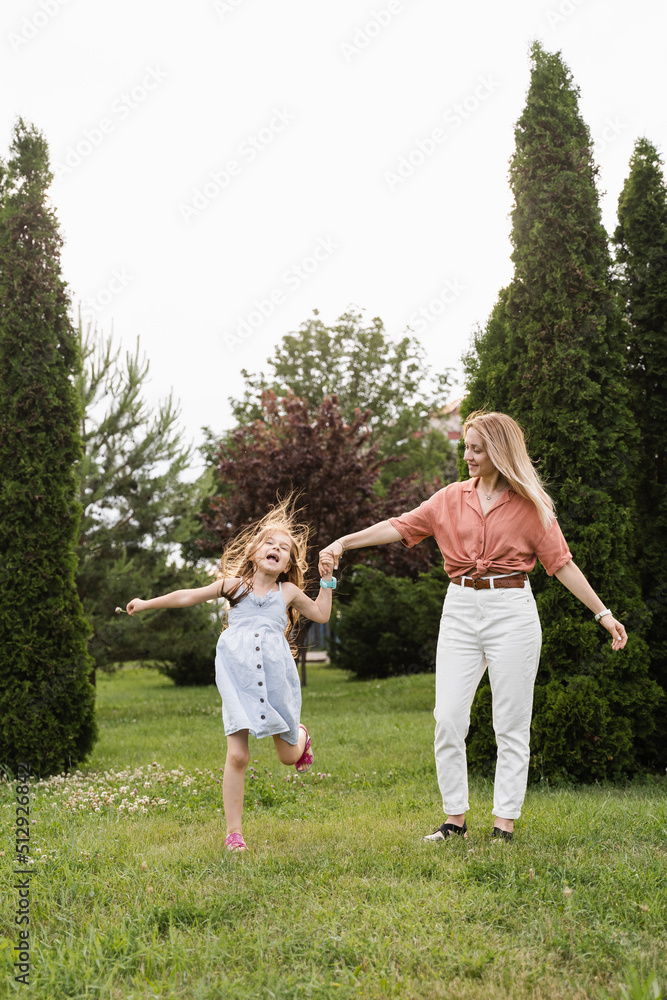 Fototapeta premium Mom and daughter having fun together. Happy family lifestyle. Daughter jumping, smiling and laughing. Love in family.